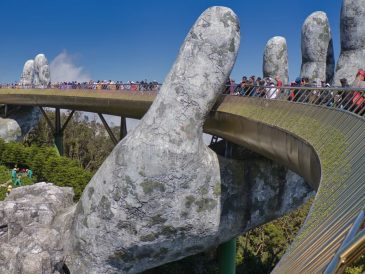 The iconic Golden Bridge with giant hand sculptures at Ba Na Hills, Vietnam, under a clear blue sky.